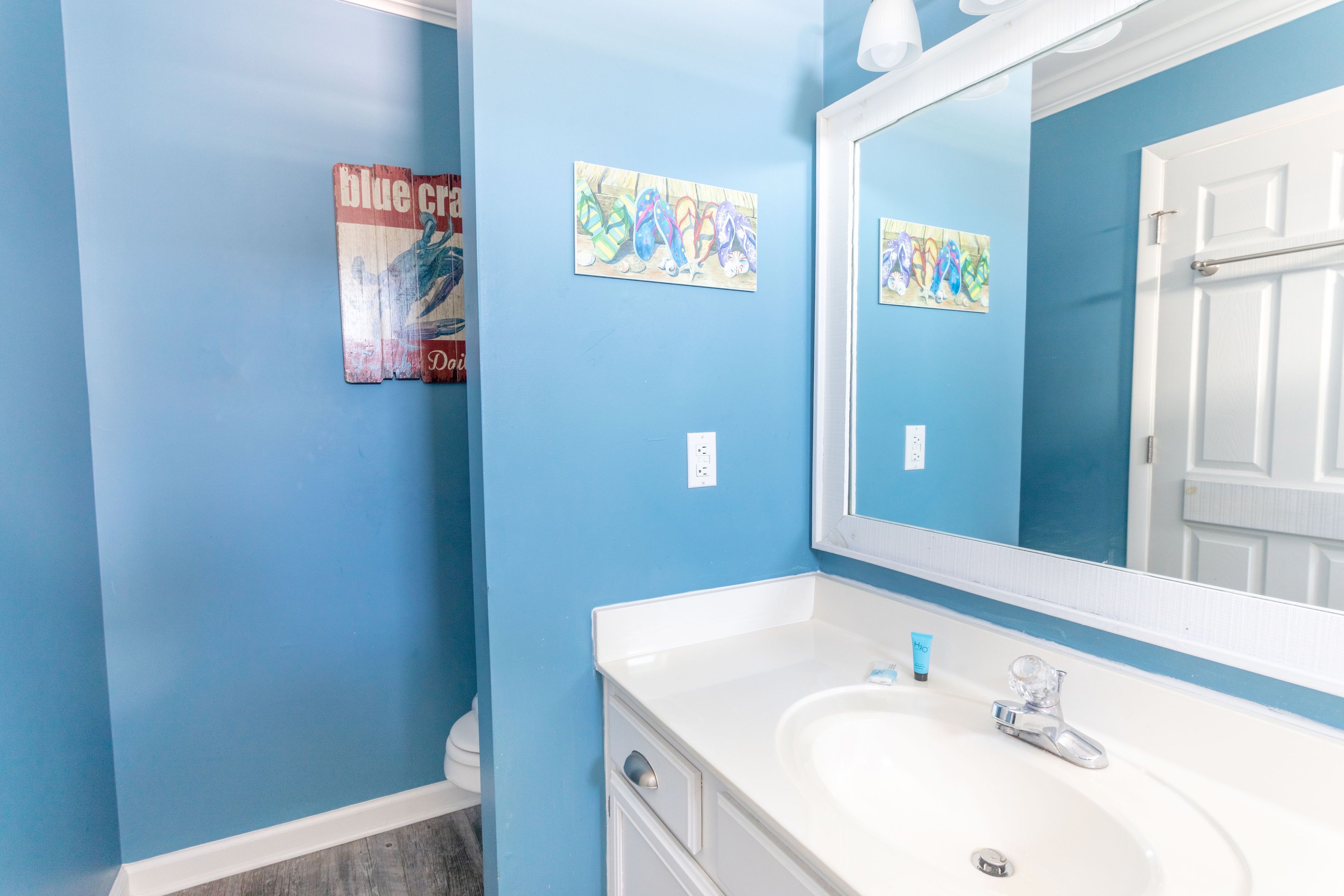 A bathroom with a white sink, blue walls, and a mirror.