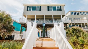 A two-story building with a balcony on the upper floor, a wooden staircase leading to the entrance, and a sign indicating a marina.