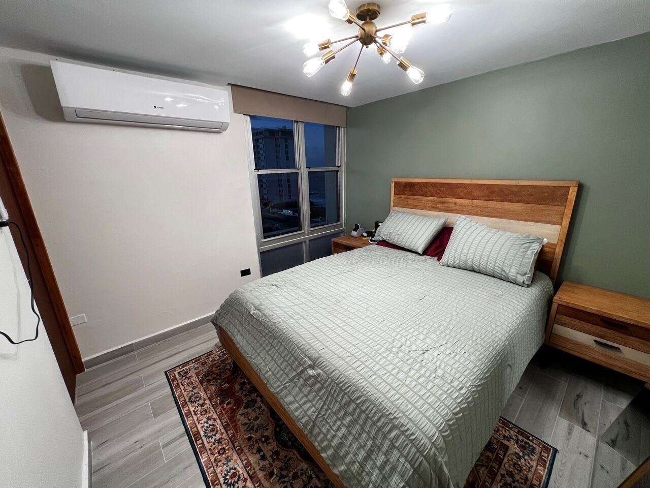 A bedroom with a bed, nightstands, a window, and a ceiling light fixture.