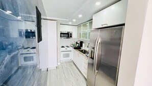Une cuisine moderne avec des armoires blanches, des appareils en acier inoxydable et un dosseret en marbre.