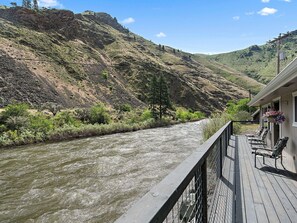 A river with a wooden deck and chairs overlooking the water. - Riverfront home just 2 miles from downtown  (Riggins)