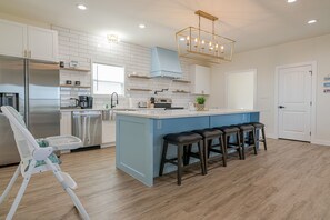 Een koelkast, een oven, een kookplaat, kookgerei, borden en bestek