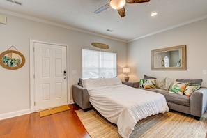 A bedroom with a bed, a sofa, a mirror, and a ceiling fan.