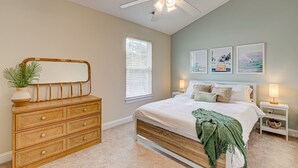 Ein Schlafzimmer mit Bett, Kommode, Deckenventilator und Wandbildern.