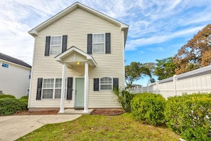 A two-story house with a front porch, a green door, and a mailbox.