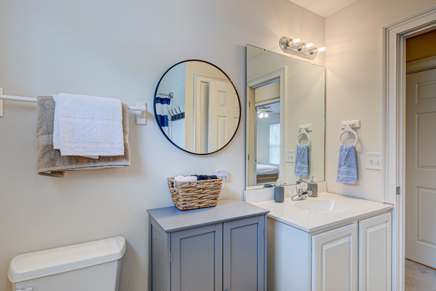 A bathroom with a toilet, a sink, a mirror, and a towel rack.
