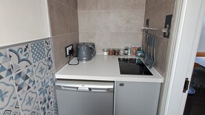 Una cuineta compacta amb rentaplats integrat, cafetera i un petit taulell amb diversos objectes de cuina.