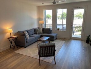 Relax in this inviting living space with a sofa, ottoman, and armchair, perfect for unwinding with a view of the outdoors.