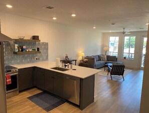 Enjoy cooking and relaxing in this spacious kitchen and living area, featuring a central island with sink, oven, and microwave, and a comfortable seating area with a sofa and coffee table.