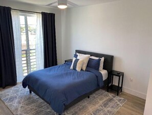 Relax in this serene bedroom with a large bed, bedside table, and window with curtains.