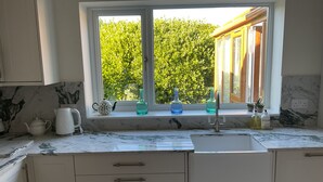 Una cocina con ventana, un lavamanos y armarios.