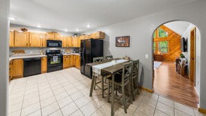 Une cuisine avec des meubles de rangement en bois, un réfrigérateur noir et une table à manger avec des chaises.