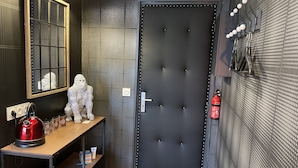 A modern bathroom with a dark door, a mirror, a towel rack, and a red kettle on a wooden shelf. - ★Studio Frères Lumière★Centre ville Dole - Wifi Netflix (Dole)