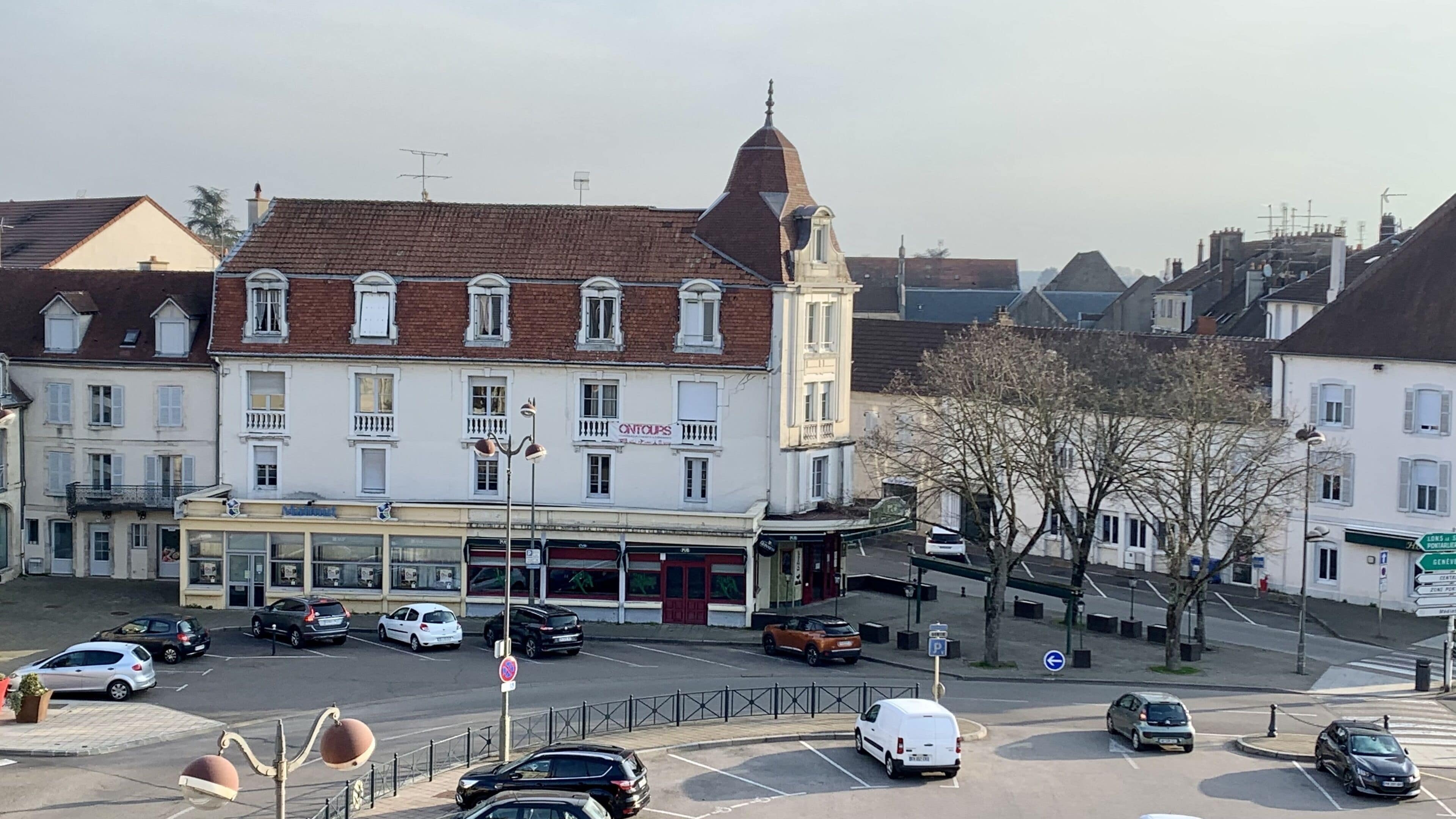 Una veduta della strada con un edificio al piano terra dove si trova un negozio chiamato 'CINTOUPS'.