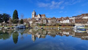 A calm river reflecting buildings and boats, with a prominent church tower in the background. - ★Studio Frères Lumière★Centre ville Dole - Wifi Netflix (Dole)