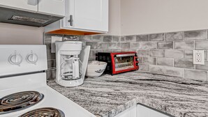 Eine Küche mit einem weißen Herd, einer Kaffeemaschine, einem Toaster und einer gefliesten Spritzschutzwand.