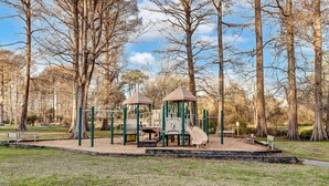 Ein Spielplatz mit Klettergerüsten und Rutschen, umgeben von Bäumen.