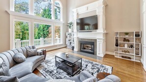 A spacious living room with a large window, a fireplace, and a television.