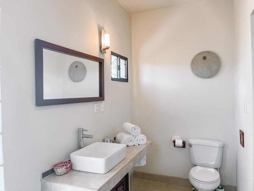 Un baño con un lavamanos blanco, un inodoro y dos espejos montados en la pared.