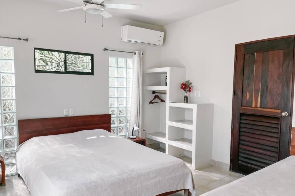 A bedroom with a bed, a wardrobe, a ceiling fan, and a window with curtains.