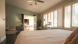 Un dormitorio con una cama grande, un escritorio y una silla. Hay una puerta que da a un comedor.