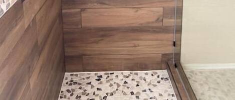 Una ducha con paredes de madera y un borde de mosaicos.