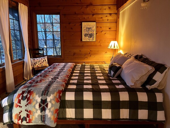 Una habitación acogedora con una cama, una silla y una ventana con cortinas.
