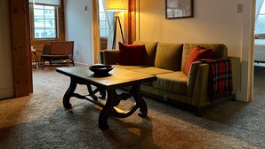 Ett mysigt vardagsrum med ett träbord, en soffa och en golvlampa.
