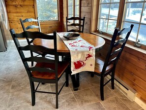 Una mesa de madera para comer con mantel festivo, rodeada por cuatro sillas negras.