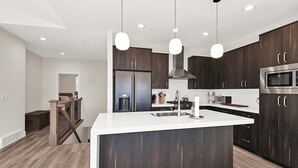 A modern kitchen with dark wood cabinets, stainless steel appliances, and pendant lighting. - Experience luxury at BMS14 | Copper Peak Retreat, a 3BR home in scenic Eden, UT. (Eden)