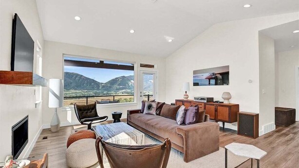 A modern living room with a large window, a sofa, a coffee table, and a TV. - Experience luxury at BMS14 | Copper Peak Retreat, a 3BR home in scenic Eden, UT. (Eden)