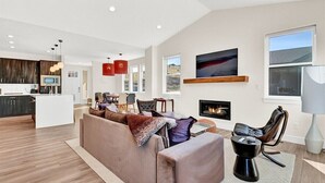 A modern living room with a large beige sectional sofa, a fireplace, and a kitchen in the background. - Experience luxury at BMS14 | Copper Peak Retreat, a 3BR home in scenic Eden, UT. (Eden)
