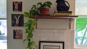 Eine Küche mit weiß gefliestem Spritzschutz, einem Holzbodenregal mit Büchern und einem Wasserkocher, sowie gerahmten Bildern.
