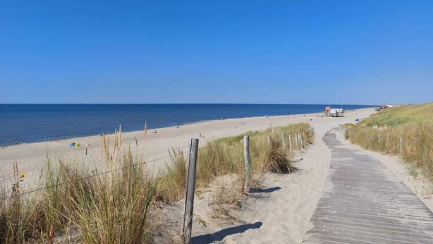 A sandy beach path leading to the ocean, with a wooden boardwalk and sparse vegetation. - Vacation home "Ons Hüske" 50sqm in a quiet location  (Dirkshorn)