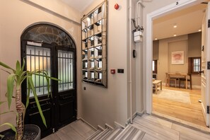 Un couloir avec une porte noire, un miroir et une plante en pot.