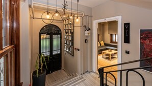 Un interior moderno con una escalera que lleva a una zona de estar, una puerta negra con panel de vidrio y una planta en maceta.