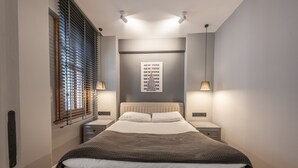 Un dormitorio moderno con una cama grande, un cabecero, una obra de arte en la pared y dos lámparas de noche.