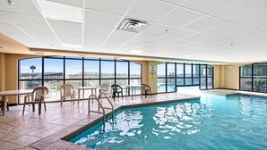 An indoor swimming pool with clear views of the cityscape through large windows. - Beachfront - 2 Kings - Heated Pool - Hot tub - Low Density (Orange Beach)
