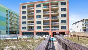 A multi-story hotel with balconies, a pool area, and a wooden boardwalk. - Beachfront - 2 Kings - Heated Pool - Hot tub - Low Density (Orange Beach)