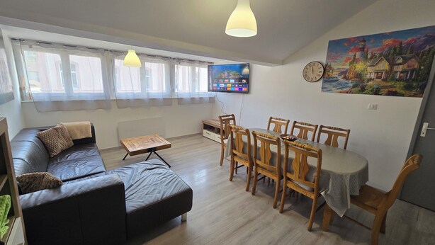 A living room with a sofa, dining table, chairs, a TV, and a painting on the wall. - Cosy gîte for 2 to 11 people near Gerardmer (Granges-Aumontzey)