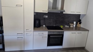 A modern kitchen with white cabinets, a built-in oven, a coffee maker, and a stove. - Cosy gîte for 2 to 11 people near Gerardmer (Granges-Aumontzey)