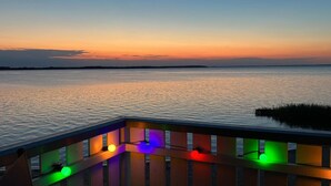 Uitzicht op het water met een houten terras en kleurrijke verlichting.