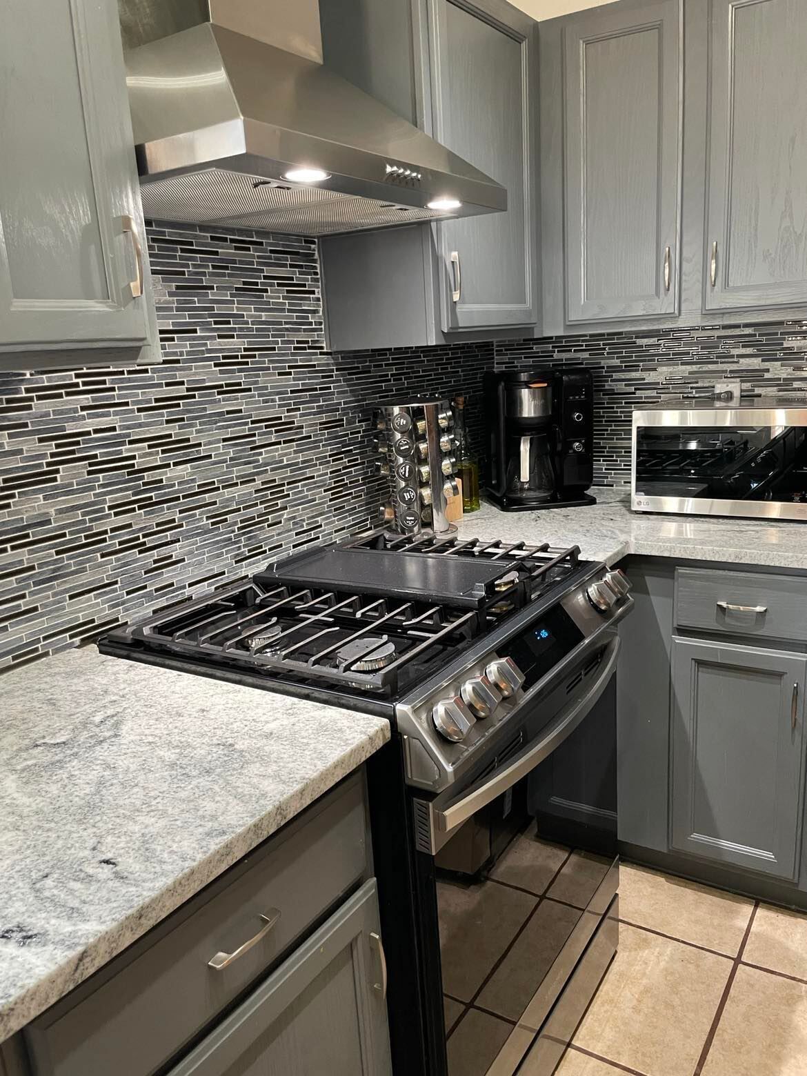 A modern kitchen with a gas stove, a coffee maker, and a microwave.