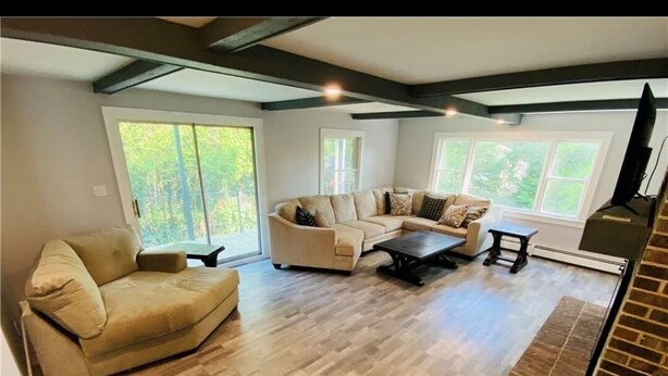 A spacious living room with a large window, a sofa, a coffee table, and a fireplace.
