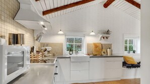 Une cuisine moderne avec des meubles blancs, une cuisinière encastrée et une grande fenêtre qui laisse entrer la lumière naturelle.