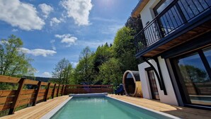Ein moderner Poolbereich mit Holzterrasse, großem Fenster und Holzlattenzaun.