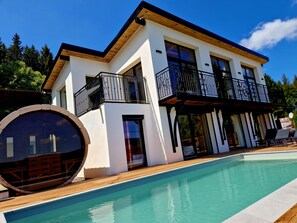 A modern two-story house with a swimming pool, wooden deck, and a large circular window. - ATPeak Lodge: Prestigious Mountain Lodging (Xonrupt-Longemer)
