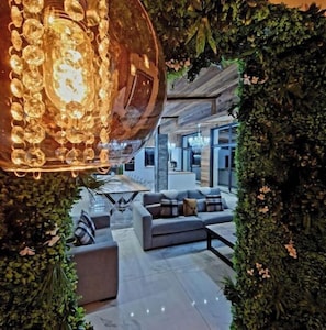 A modern interior with a large spherical light fixture, a seating area with sofas and a coffee table, and a backdrop of green foliage. - ATPeak Lodge: Prestigious Mountain Lodging (Xonrupt-Longemer)