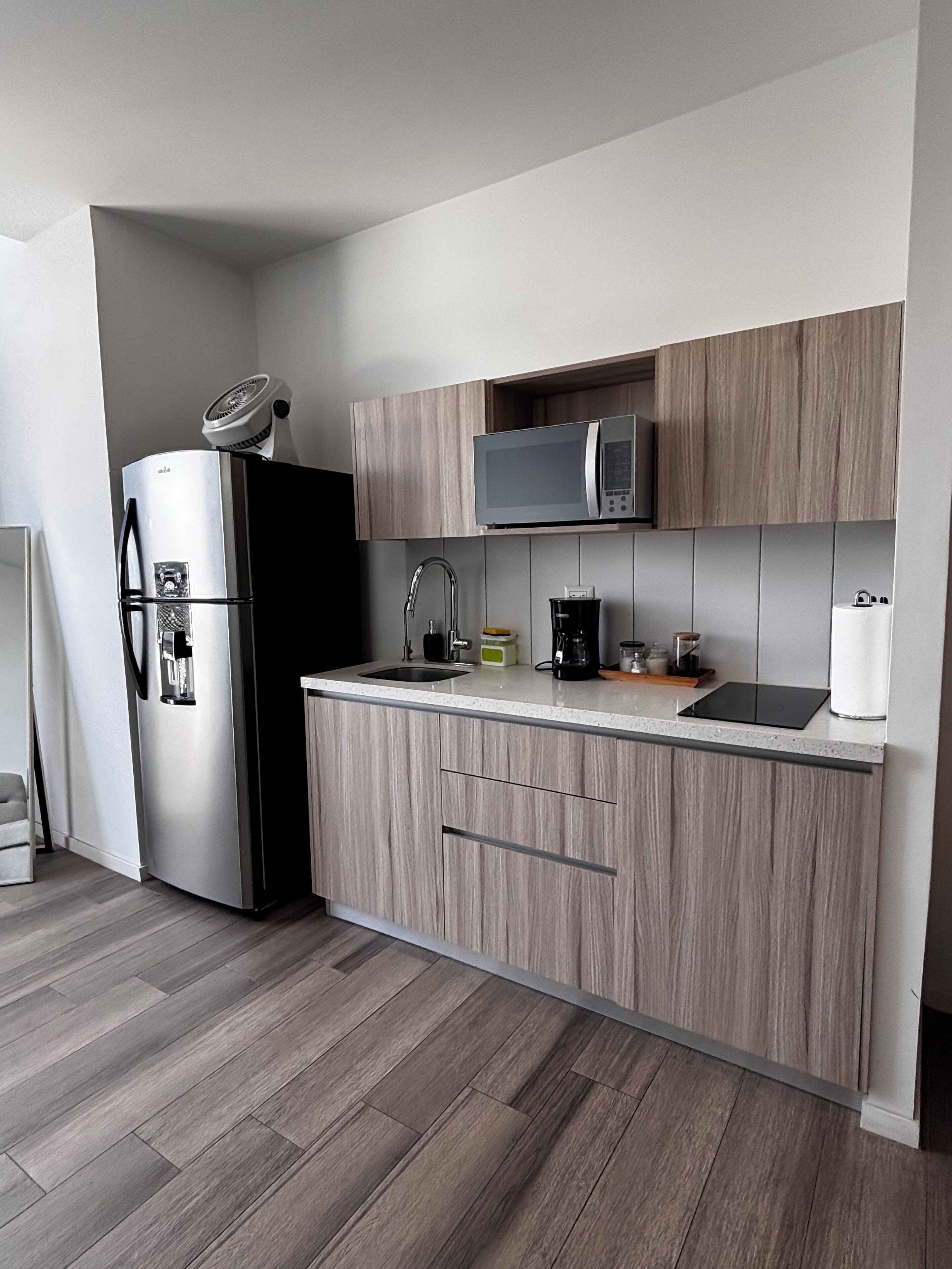 Cocina moderna con refrigerador de acero inoxidable, microondas y cafetera.