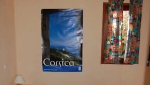 Un dormitori amb un llit, un cartell a la paret i una finestra amb cortines.